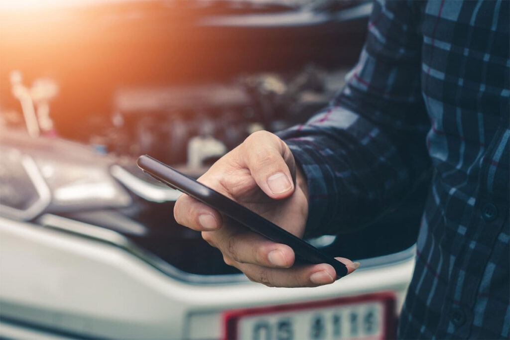 Bărbat solicitând ajutor prin telefon în fața unei mașini avariate – intervenție rapidă de vulcanizare mobilă.